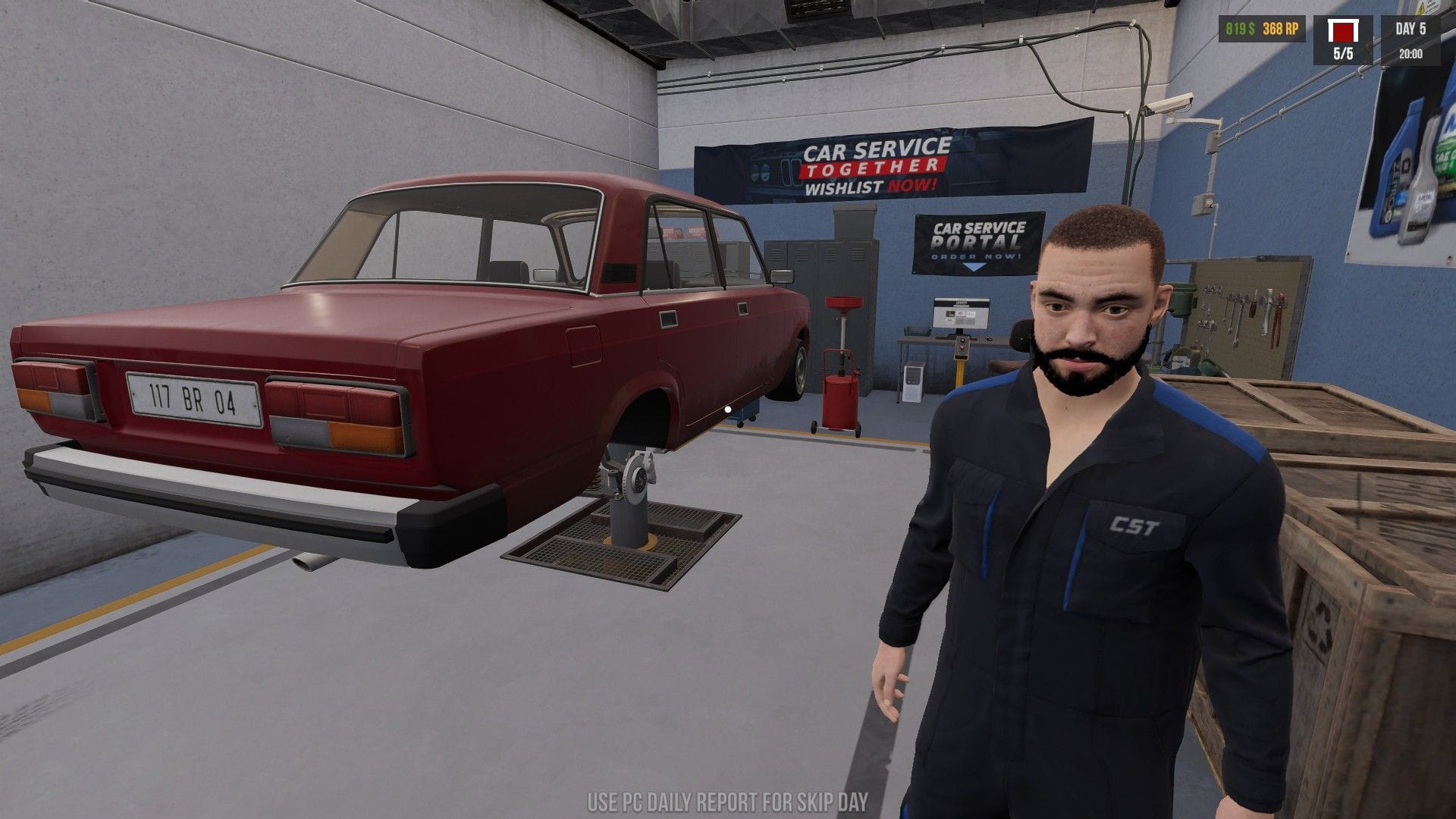 Jonty poses for the camera in front of a red car raised on another lift. 