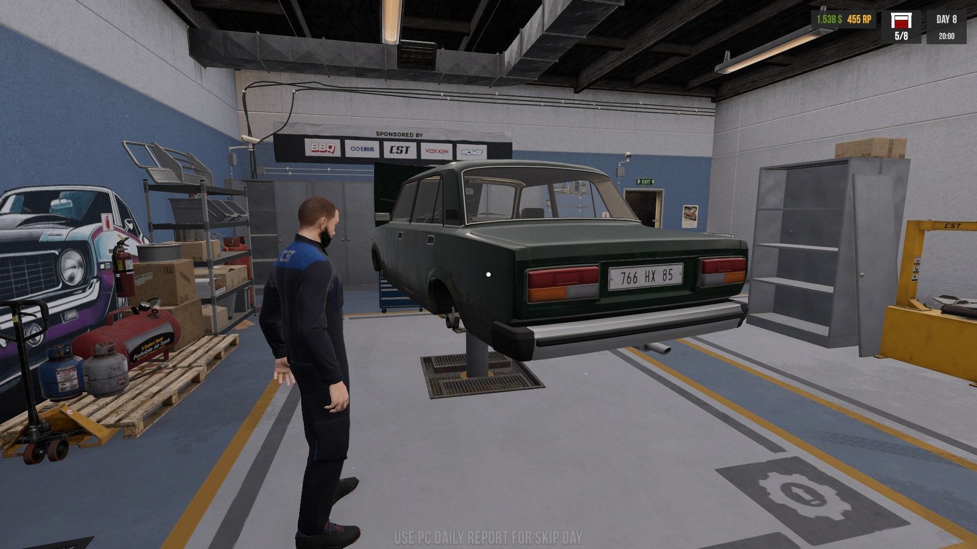 Jonty examines the wheel area of the green car on a lift.