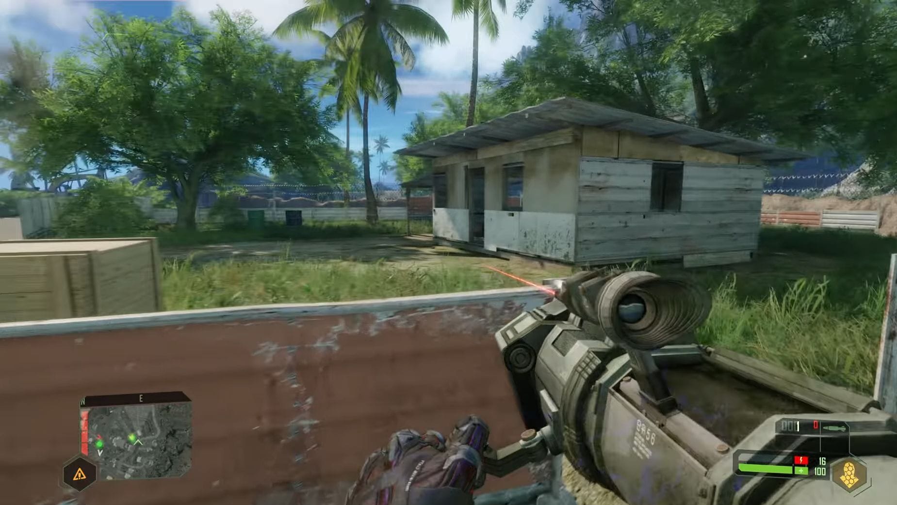 The hero of Crysis holds a bazooka while looking at a shack in the jungle.