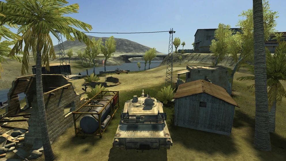 A tank sits among houses and trees under a blue sky.