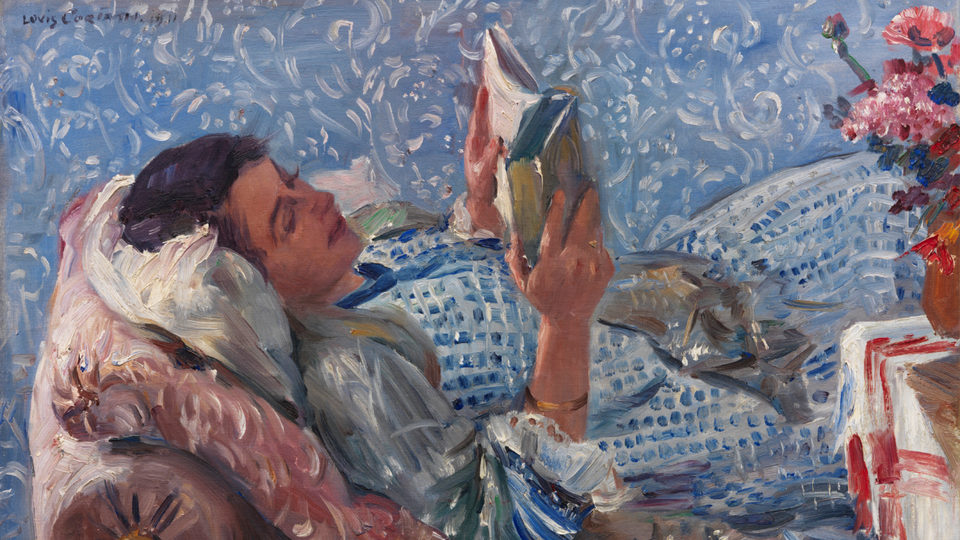 A woman reclines on a chaise longue and reads a book, contentedly.